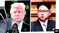 Žena sa kišobranom prolazi ispred ogromnog ekrana u Tokiju, na kojem se vide američki predsednik Donald Tramp i severnokorejski lider Kim Džong Un (Foto: Koji Sasahara/AP) 