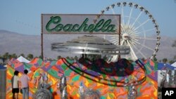 FILE - Festival-goers view the "Coachella Bound" art installation at the campgrounds at The Coachella Music and Arts Festival.