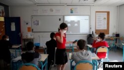 Una maestra y alumnos en Francia usan máscara, en una mezcla de clases en línea y presenciales en Nantes, al reabrir el país en mayo de 2020.