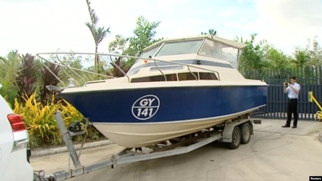 An officer takes pictures of a boat, which Australian police have seized in Cairns, Queensland, Australia in this still image taken from video, May 11, 2016.