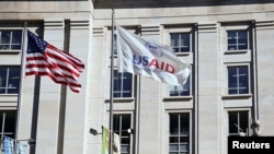 FILE: Bendera Amerika dan bendera USAID berkibar di luar gedung USAID di Washington, D.C.