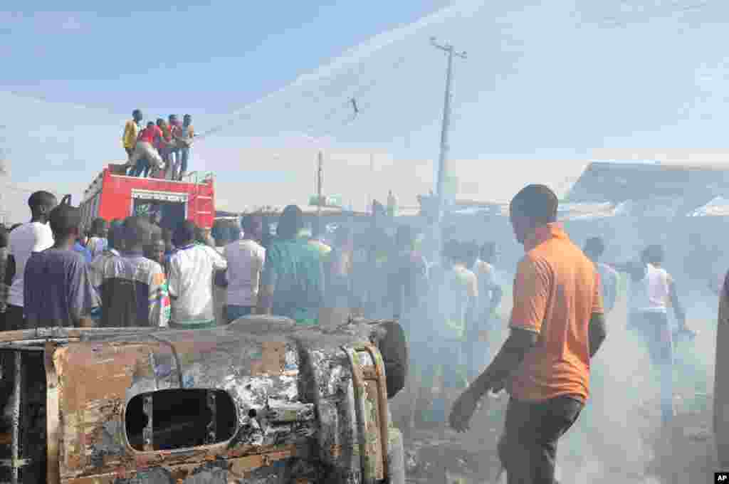 Mutane sun taru kusa da inda bam ya tashi cikin mota a kasuwar &quot;Monday Market&quot; ta Maiduguri, talata 1 Yuli, 2014. Mutane da dama sun mutu, akasarinsu mata tsoffi da almajirai dake bara.