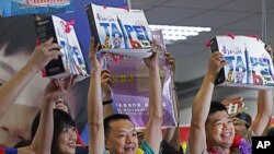 The first individual Chinese tourists hold up gift bags as they arrive at the Songshan airport in downtown Taipei, Taiwan, June 28, 2011