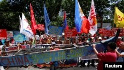 Para demonstran memperlihatkan bagian dari kapal nelayan dengan slogan-slogan anti China dalam unjuk rasa memprotes pertikaian klaim Laut China Selatan, di luar Konsulat China, di Makati City, Metro Manila, Filipina, 12 Juli 2016. REUTERS/Erik