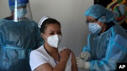 La enfermera Cristina Chango recibe su primera dosis de la vacuna Pfizer-BioNtech contra COVID-19 en el Hospital Pablo Arturo Suárez en Quito, Ecuador, el jueves 21 de enero de 2021.