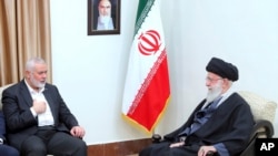 In this photo released by an official website of the office of the Iranian supreme leader, Hamas chief Ismail Haniyeh, left, speaks with Ayatollah Ali Khamenei in Tehran on March 26, 2024. A portrait of the late Iranian revolutionary founder Ayatollah Khomeini hangs on the wall.