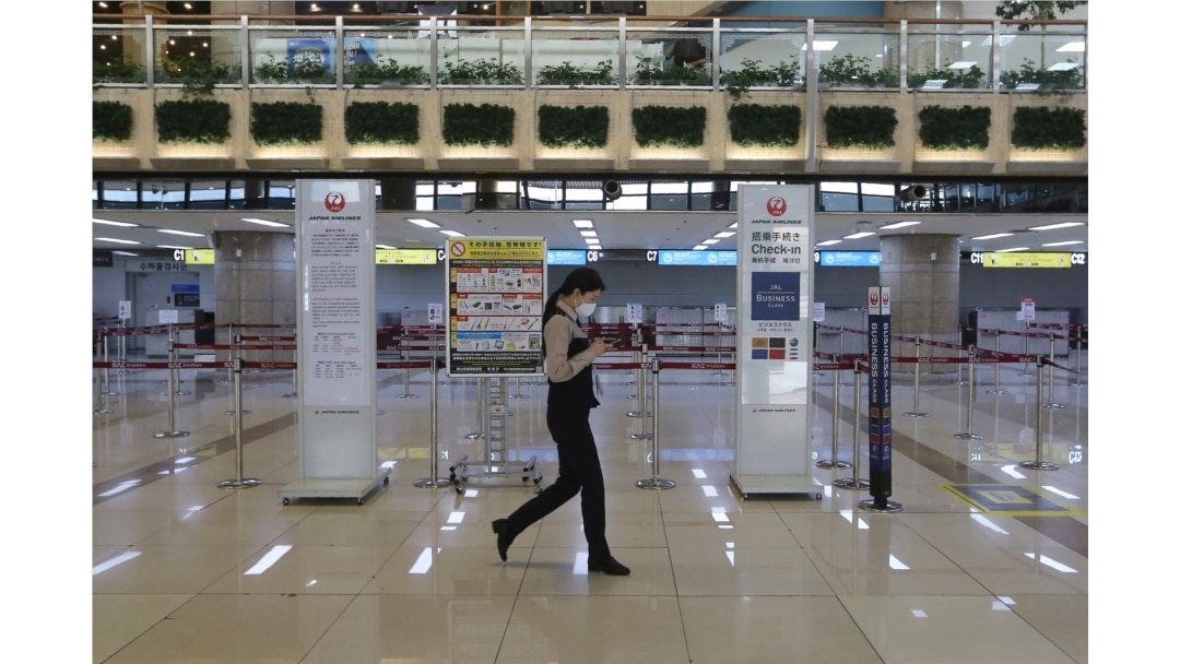 A Gimpo Airport official wearing a face mask passes by check-in counters of Japan Airlines at Gimpo Airport in Seoul, South Korea, Monday, March 9, 2020. South Korea announced on Friday, March 6, it will end visa-free entry for Japanese citizens.