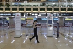 A Gimpo Airport official wearing a face mask passes by check-in counters of Japan Airlines at Gimpo Airport in Seoul, South Korea, Monday, March 9, 2020. South Korea announced on Friday, March 6, it will end visa-free entry for Japanese citizens.