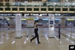 A Gimpo Airport official wearing a face mask passes by check-in counters of Japan Airlines at Gimpo Airport in Seoul, South Korea, Monday, March 9, 2020. South Korea announced on Friday, March 6, it will end visa-free entry for Japanese citizens.