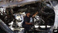 A Palestinian Hamas police officer examines a destroyed car after an explosion in Gaza City, 3 Nov. 2010.