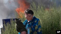 Người phụ nữ khóc gần nơi căn nhà đang bốc cháy của bà ở thành phố Slovyansk, trong vùng Donetsk, miền đông Ukraine 30/6/14