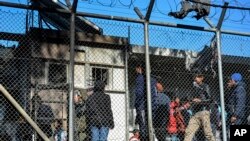 Migrants stand outside container houses in Moria refugee camp on the northeastern Aegean island of Lesbos, Greece, March 16, 2020.