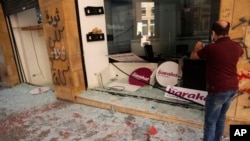 A man takes pictures of a shop damaged during an anti-government protest, in Beirut, Lebanon, June 12, 2020. 