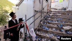 FILE - Ultra-Orthodox Jews look at stairs at the site of a deadly stampede that marred a religious festival in Mount Meron, northern Israel, April 30, 2021.