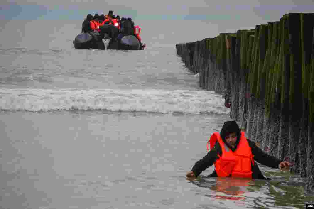 A migrant returns to shore after attempting to cross the English Channel to reach Great Britain on a smuggler&#39;s inflatable dinghy at Sangatte beach near Calais, northern France.