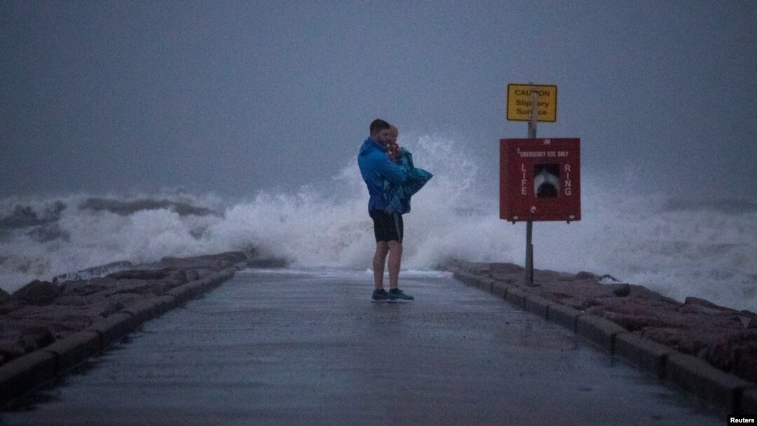 Warga setempat, John Smith menggendong putranya yang baru berusia 18 bulan, Owen, berdiri di tepi pantai Galveston, Texas, menjelang badai tropis Nicholas, 13 September 2021. (REUTERS/Adrees Latif/File Photo)