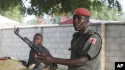 Police officers armed with AK-47 rifles stand guard at sandbagged bunkers along a major road in Maiduguri, Nigeria.