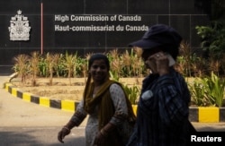 FILE - Women walk past the main gate of the Canadian High Commission, in New Delhi, Oct. 17, 2024.