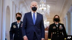 Presiden AS Joe Biden berjalan bersama Marsekal Jacqueline Van Ovost (kiri) dan Letnan Jenderal Laura Richardson sebelum berbicara dalam perayaan Hari Perempuan Internasional, Senin (8/3). 