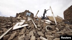 A youth throws a plank of wood away from a pile of rubble of a house destroyed during an air strike carried out by the Saudi-led coalition in Faj Attan village, Sanaa, Yemen, May 7, 2015. 