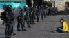 Un manifestante se sienta frente a una escuadrón de policías con equipo antidisturbios durante una protesta contra el gobierno en Bogotá, Colombia, el lunes 21 de septiembre de 2020. 