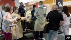 FILE - Arriving passengers are screened by health workers at the airport in Sydney, Australia, Feb. 12, 2021.