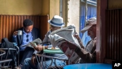 FILE - In this Oct. 10, 2016 file photo, Ethiopian men read newspapers during a declared state of emergency and internet shutdown in Addis Ababa, where the lawmakers on Feb. 13, 2020 approved a controversial law aimed at curbing hate speech. 