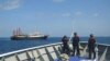 FILE - In this April 27, 2021, photo provided by the Philippine Coast Guard, its personnel patrol beside ships said to be Chinese militia vessels at Sabina Shoal in the South China Sea.