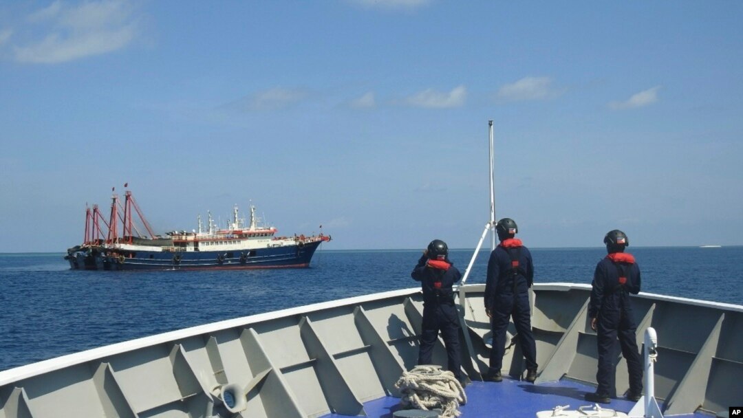 FILE - In this April 27, 2021, photo provided by the Philippine Coast Guard, its personnel patrol beside ships said to be Chinese militia vessels at Sabina Shoal in the South China Sea.
