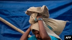 A Rohingya man carries relief aid at a camp in Teknaf, Bangladesh, Aug. 21, 2019. 