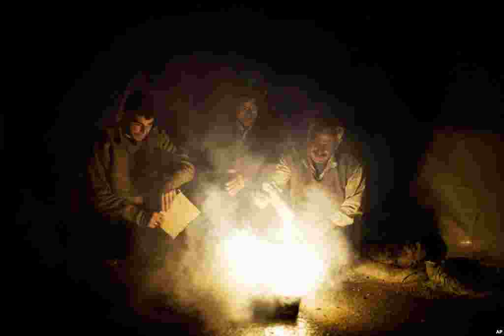 Men use a fire to boil water near their tent at a refugee camp near the Turkish border, in Azaz, Syria, December 9, 2012.
