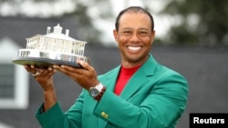 FILE - Tiger Woods wears his green jacket and holds his trophy after winning the 2019 Masters in Augusta, Georgia, April 14, 2019.