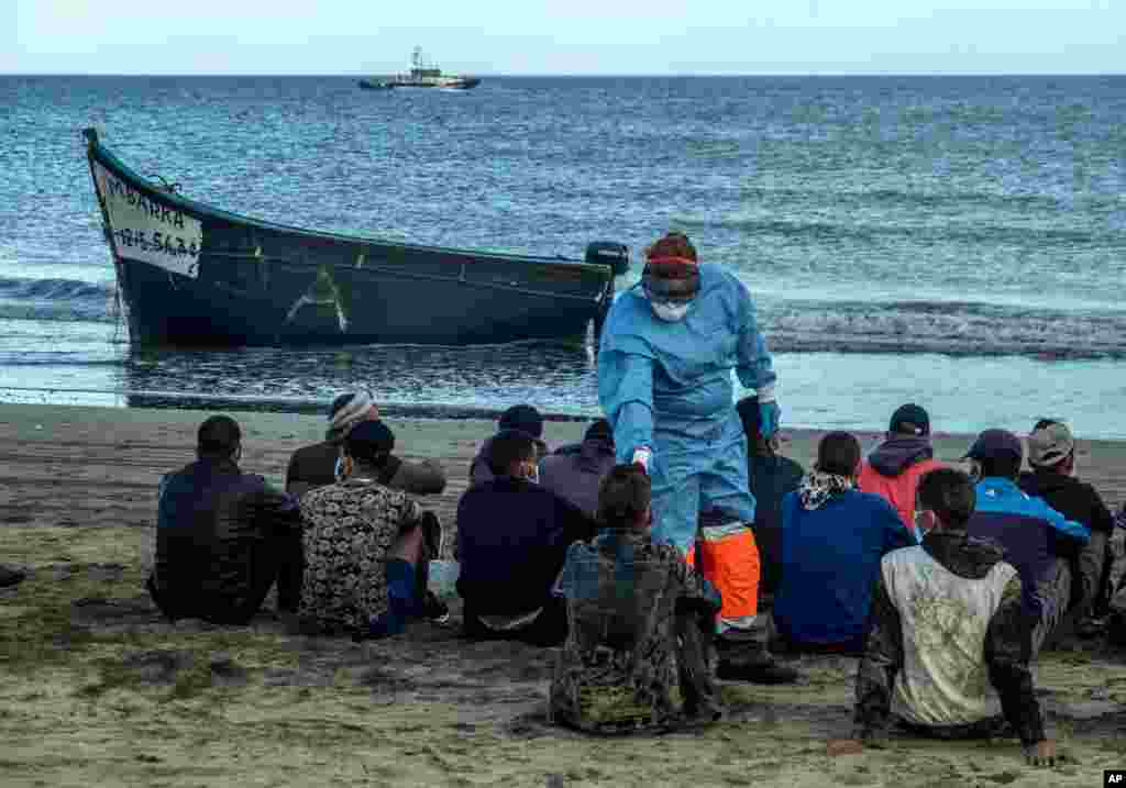Migrants from Morocco have their temperatures checked because of the coronavirus, upon arrival at the coast of the Canary Islands, Spain, after crossing the Atlantic Ocean in a wooden boat, Oct.20, 2020.