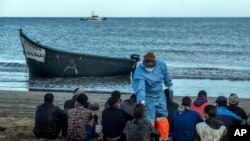 FILE- Migrants from Morocco have their temperatures checked because of the coronavirus, upon arrival at the coast of the Canary Islands, Spain, after crossing the Atlantic Ocean in a wooden boat, Oct. 20, 2020.