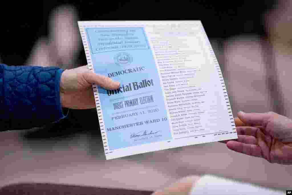 A woman takes a Democratic ballot to vote in Manchester, N.H., Feb. 11, 2020.
