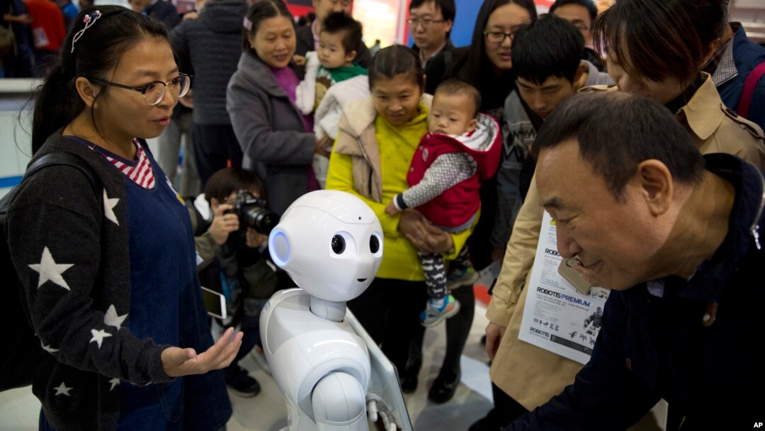 FILE - Visitors crowd around Pepper, a companion robot, during the World Robot Conference in Beijing. China, Oct. 21, 2016. 