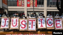 People hold placards to form the word "Justice" during a protest against the military coup in Yangon, Myanmar, Feb. 22, 2021. 