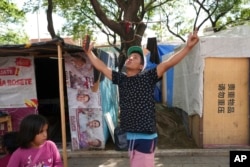 Venezuelan migrant Eliezer López spreads his arms in celebration after securing an appointment to seek asylum through the U.S. Customs and Border Protection's mobile app, CBP One, at a migrant tent encampment in Mexico City, Friday, July 5, 2024.