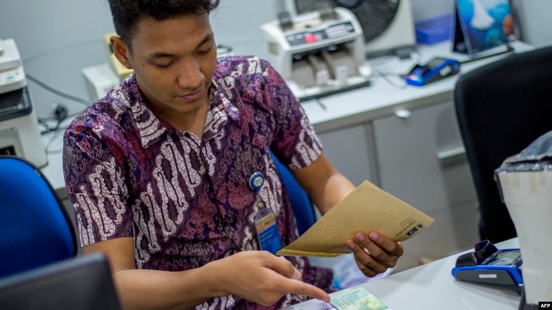 Seorang petugas bank sedang mempersiapkan uang tunai untuk para nasabah yang mendatangi tempat-tempat penukaran uang menjelang liburan Idul Fitri lalu, di Jakarta, 25 Mei 2018.
