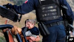 Rodeados por autoridades mexicanas fuertemente armadas, miembros de la familia LeBaron lloran en el sitio donde fueron asesinados nueve ciudadanos estadounidenses, tres mujeres y seis niños, relacionados con esa familia.