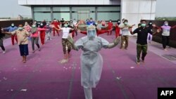 A gymnastics instructor wearing personal protective equipment (PPE) leads a morning exercise for patients of the COVID-19 coronavirus at a hotel designated to treat asymptomatic patients in Karawaci, Indonesia's Banten province.