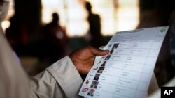 FILE - Kenyan voter holds a presidential ballot at a polling station in the Kibera slum in a general election in Nairobi, Kenya.