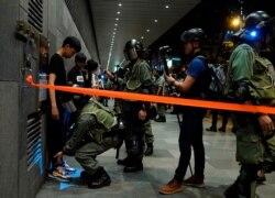 Riot policemen frisk bus passengers in Hong Kong, Sept. 28, 2019.