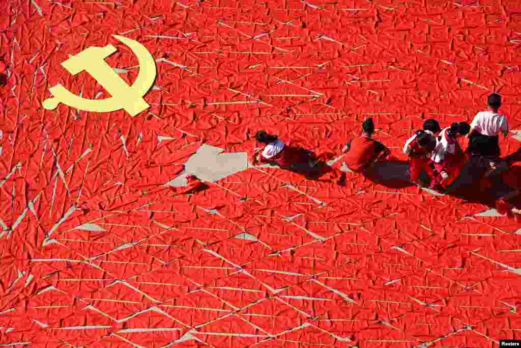 Students use red scarves to make a flag of the Communist Party of China, ahead of the 19th National Congress of the Communist Party, at a primary school in Linyi, Shandong province.