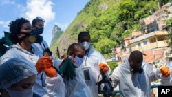 Para relawan berdoa bersama sebelum mulai menyemprotkan disinfektan untuk mencegah penyebaran virus corona di perkampungan kumuh Santa Marta, di Rio de Janeiro, Brazil, Sabtu, 28 November 2020. (Foto: Reuters)