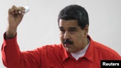 Presiden Venezuela Nicolas Maduro menunjukkan kertas suaranya saat memberikan suara di Caracas, Minggu (30/7) lalu. 