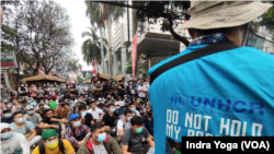 Para pengungsi dari Afghanistan menyampaikan suara mereka sementara polisi mengawasi mereka di depan kantor UNHCR, Jakarta, 24 Agustus 2021. (Foto: VOA/Indra Yoga)