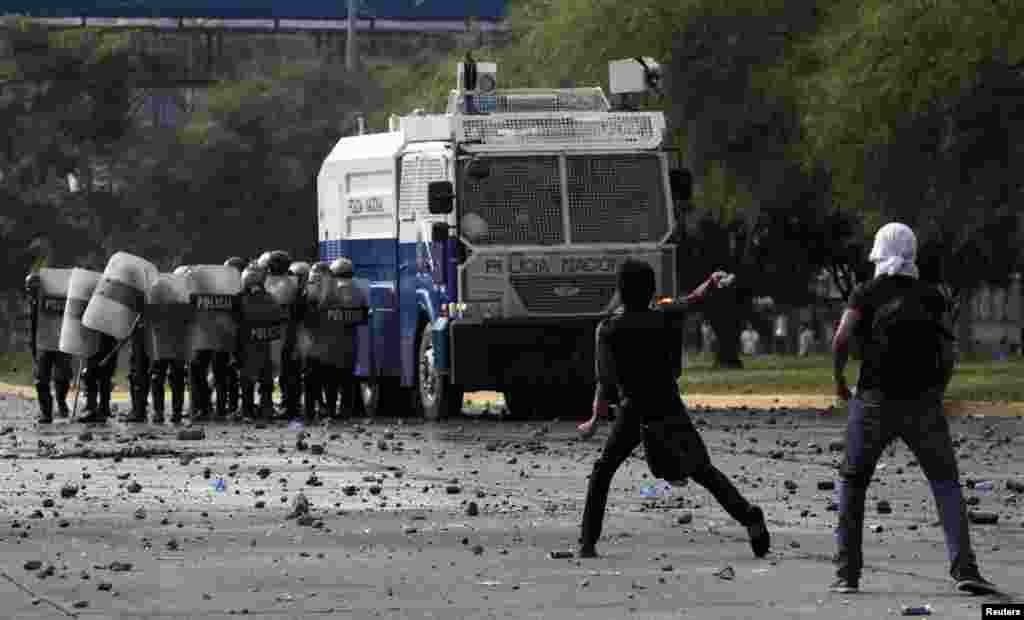 Seorang mahasiswa melemparkan batu ke arah polisi anti huru-hara di Universitas Nasional Honduras di Tegucigalpa, dalam aksi untuk memrotes hasil pemilu di Honduras. 