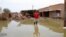 FILE - A man gestures as he wades through a flooded road in the town of Salmaniya, about 35 km southwest of the capital, Khartoum, Sudan, Sept. 17, 2020.