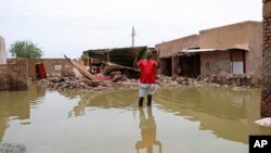 FILE - A man gestures as he wades through a flooded road in the town of Salmaniya, about 35 km southwest of the capital, Khartoum, Sudan, Sept. 17, 2020.